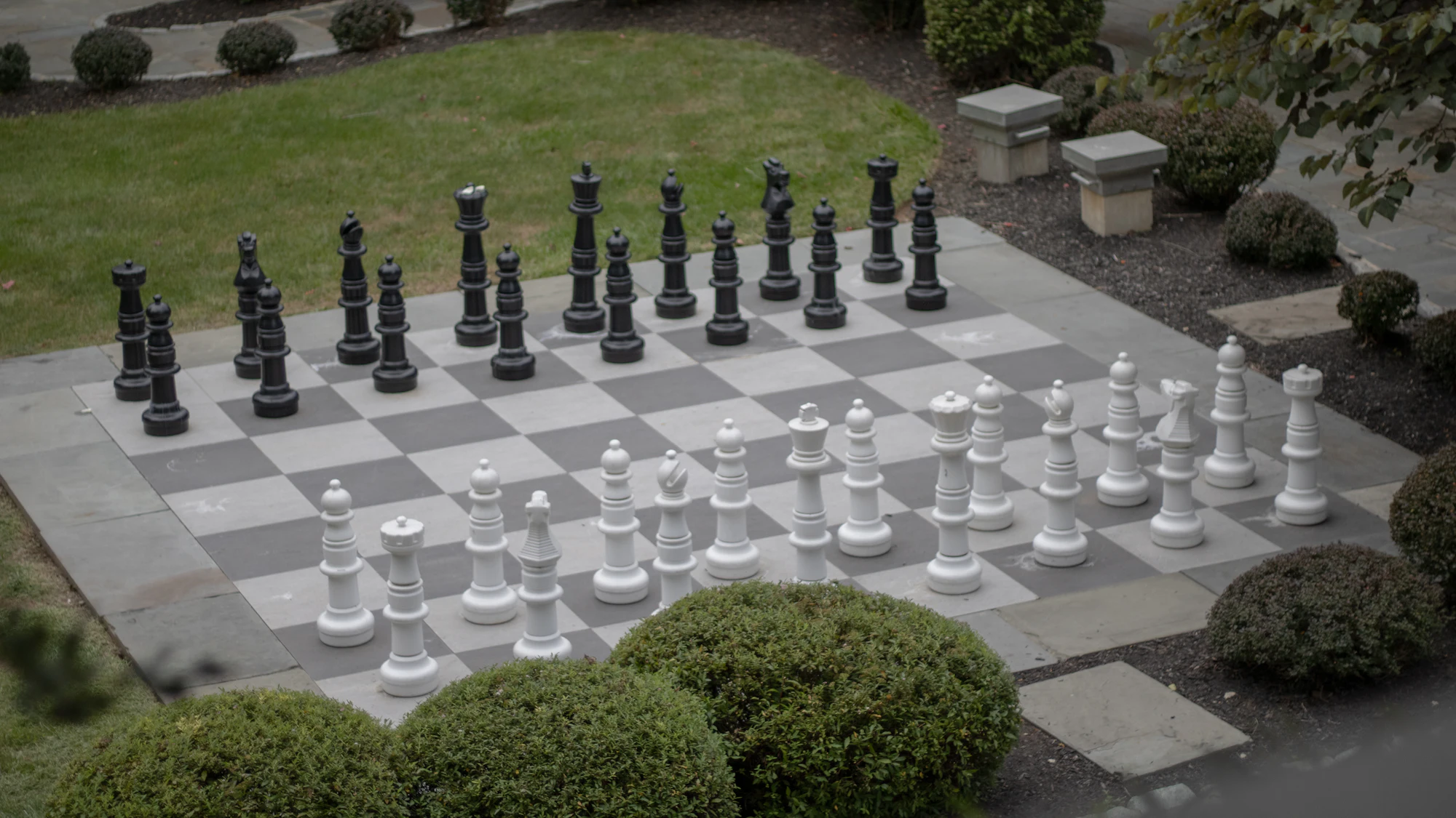 Giant chess set laid out on a garden lawn mid-game