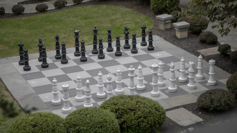 Giant chess set laid out on a garden lawn mid-game