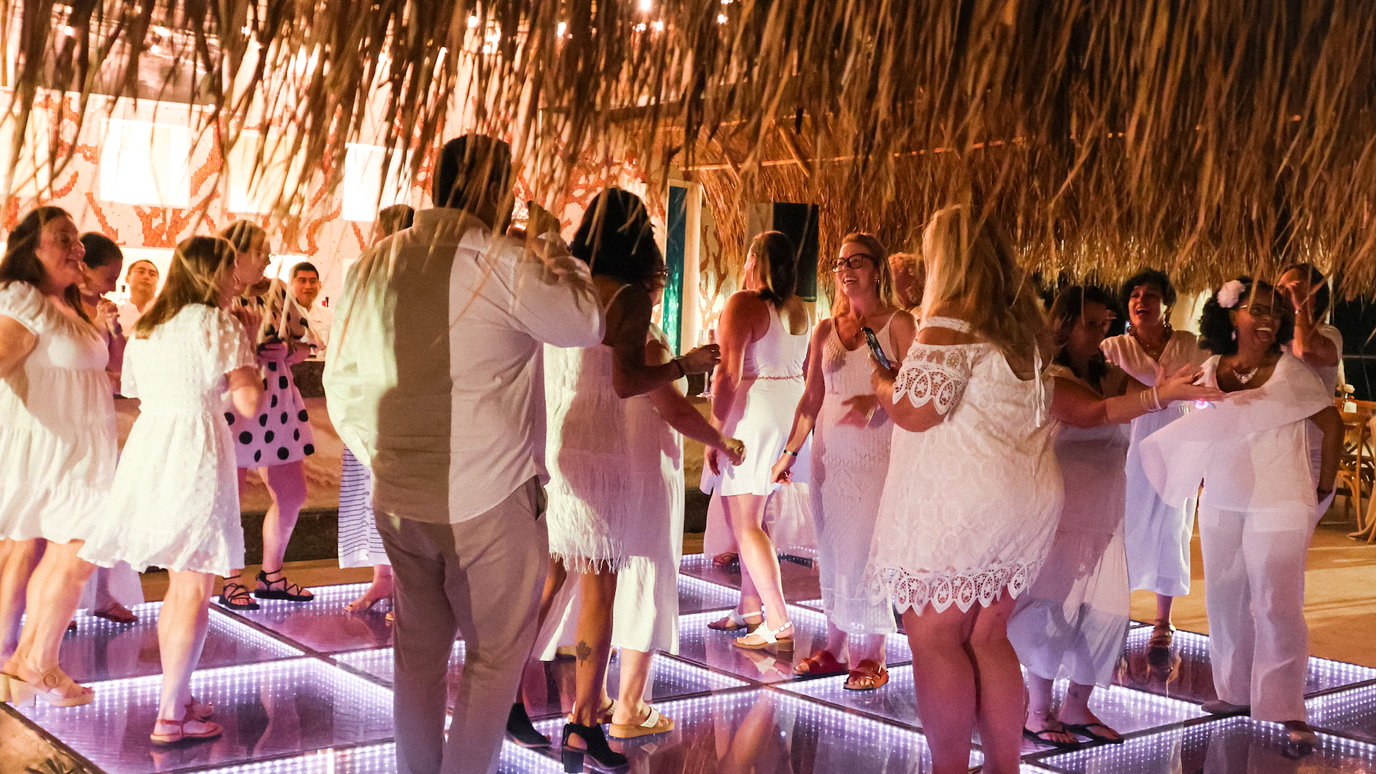 Guests dancing on a glowing LED dance floor at a wedding reception