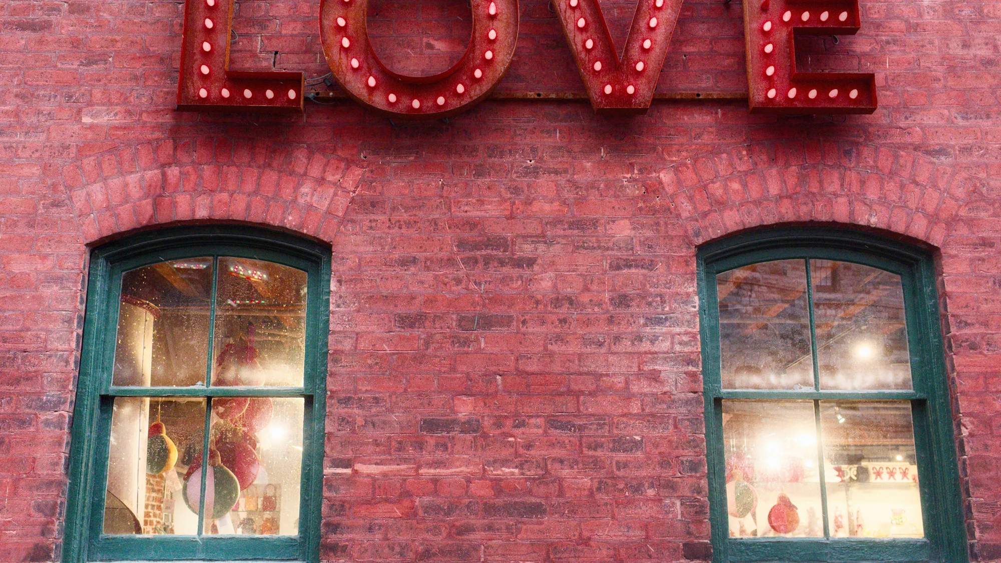 Giant red marquee LOVE letters glowing against a brick wall at dusk