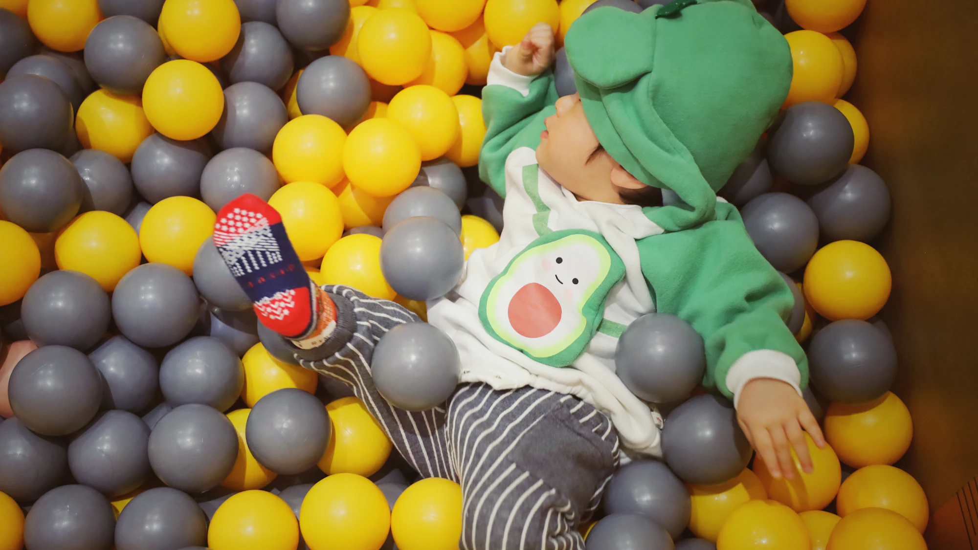 Happy toddler playing in a ball pit full of colourful balls
